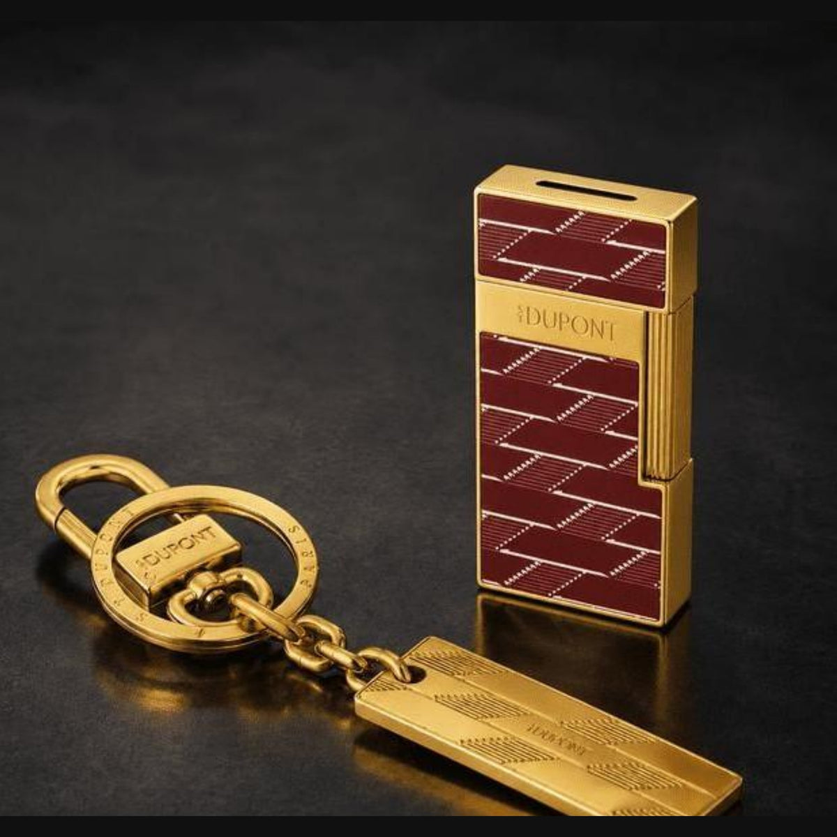 S.T. Dupont holiday set SET-GS-01 - Biggy lighter in burgundy Monogram 1872 lacquer with gold finish beside a gold 1872 keyring